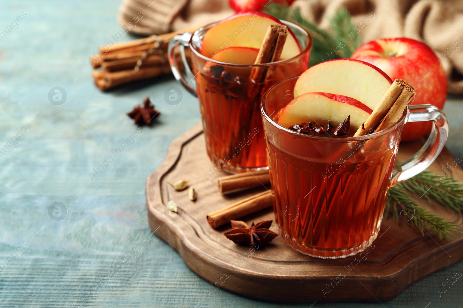 Photo of Aromatic hot mulled cider on light blue wooden table. Space for text