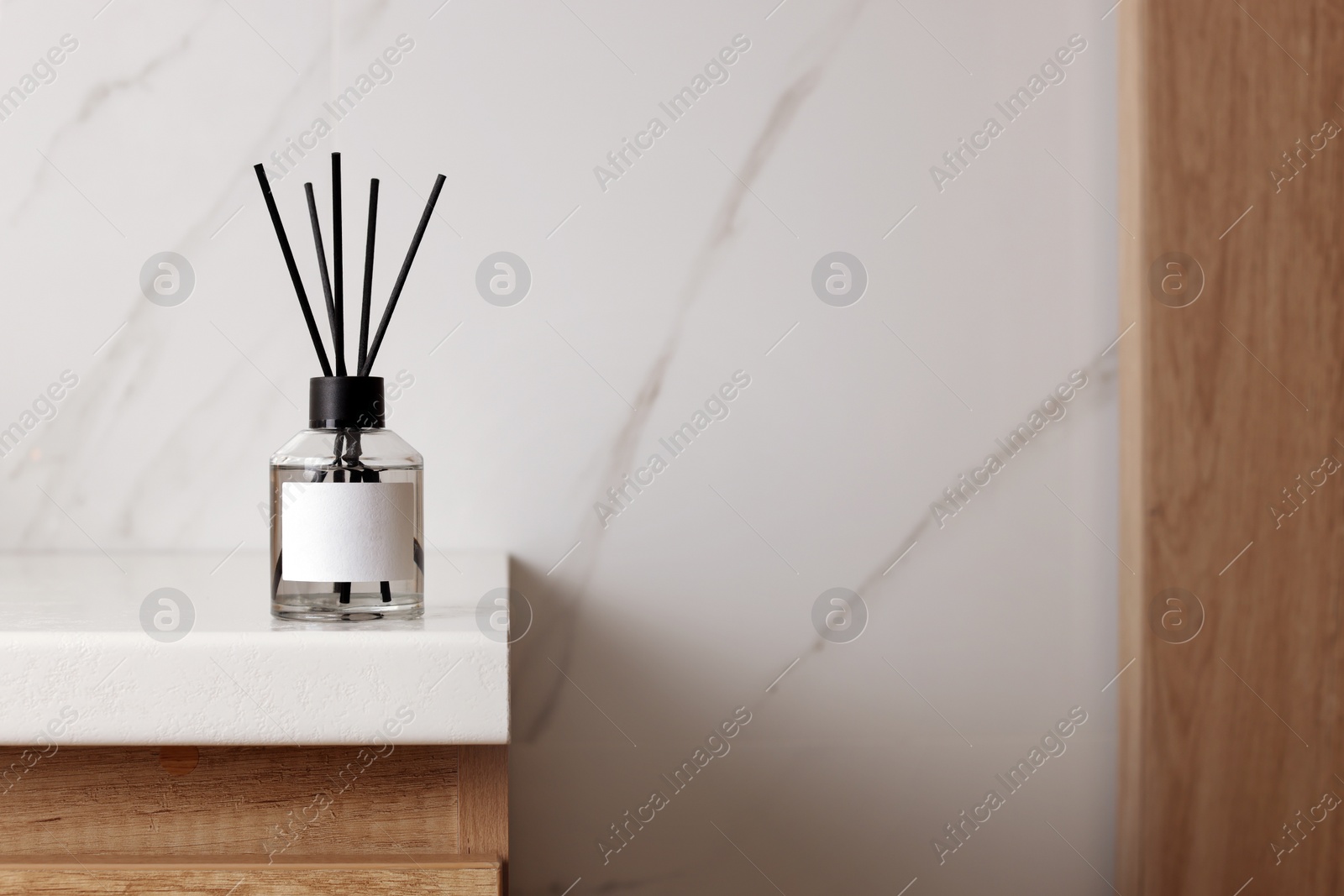 Photo of Aromatic reed air freshener on white table indoors, space for text