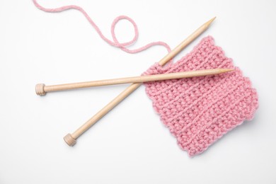 Photo of Pink knitting and wooden needles on white background, top view