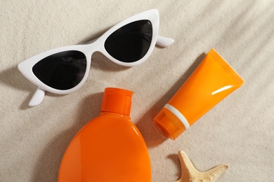 Photo of Flat lay composition with sun protection cosmetic products on sand