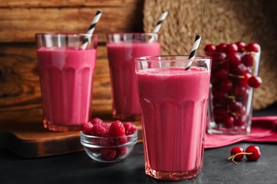 Photo of Tasty fresh milk shake with berries on black table. Space for text