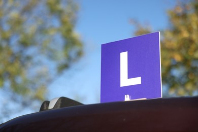 Photo of L-plate on car outdoors, low angle view with space for text. Driving school
