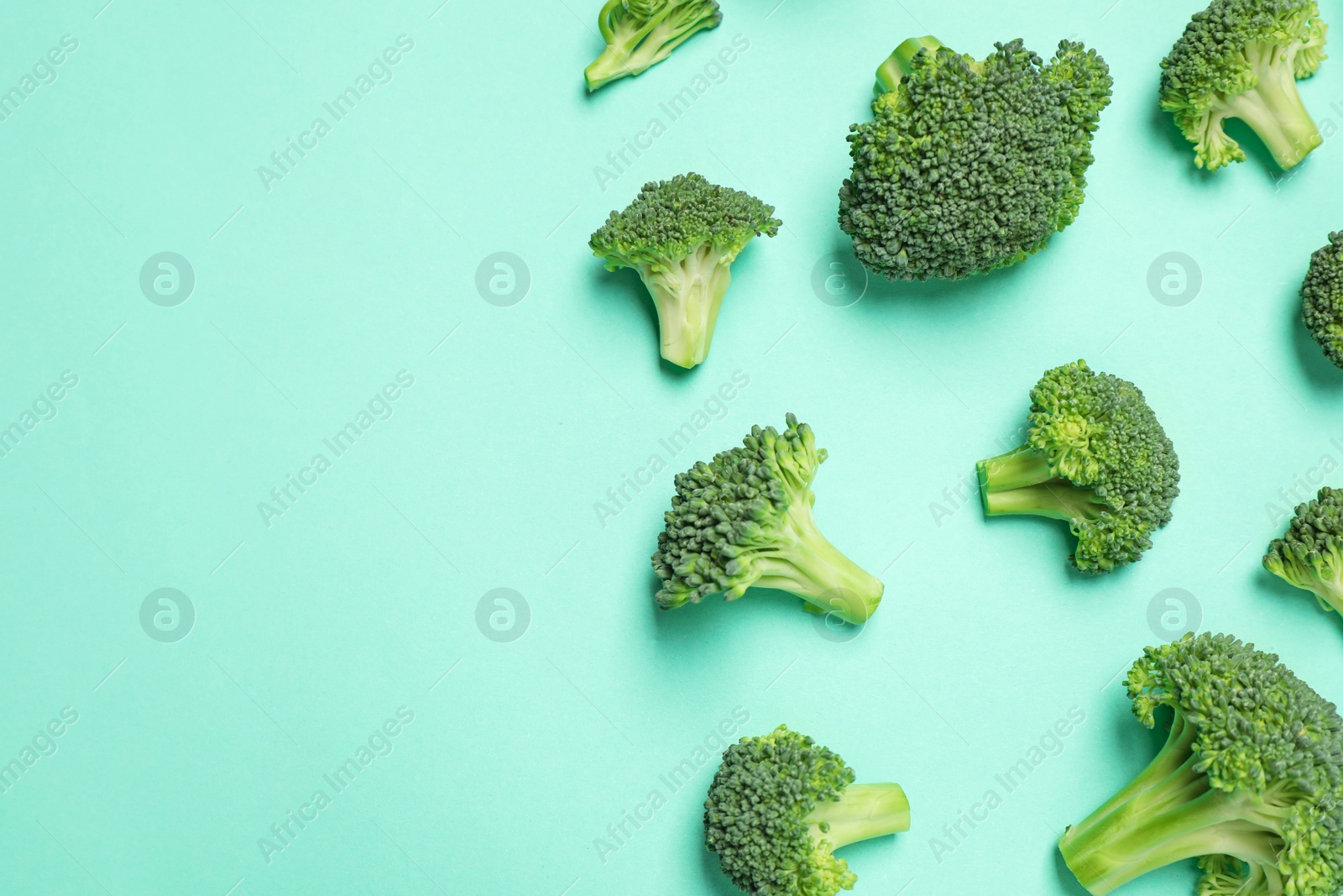 Photo of Fresh tasty broccoli on turquoise background, flat lay. Space for text