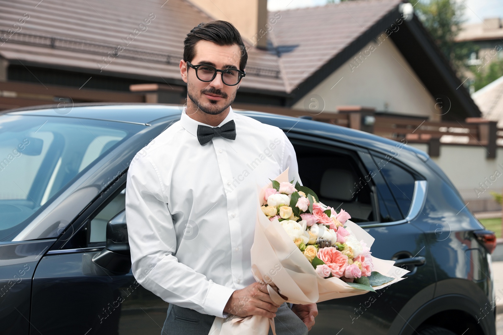 Photo of Young handsome man with beautiful flower bouquet near car outdoors