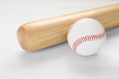 Photo of Baseball bat and ball on white wooden table. Sports equipment