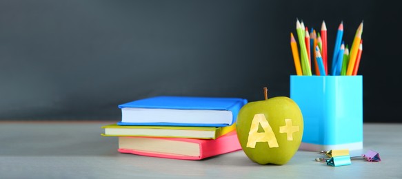 Image of Apple with carved letter A and plus symbol as grade. School stationery on white table in classroom. Banner design with space for text