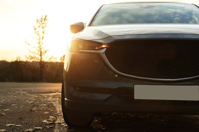 Photo of Black modern car parked on road at sunset, closeup