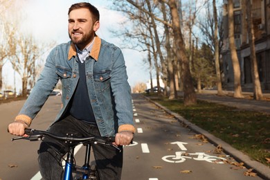 Happy handsome man riding bicycle on lane in city
