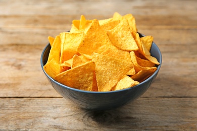 Photo of Tasty mexican nachos chips in color bowl on wooden table