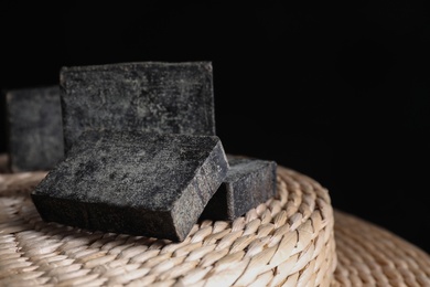 Photo of Natural tar soap on wicker pouf, closeup