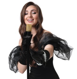 Beautiful young woman in stylish black dress with microphone singing on white background