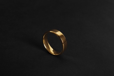 Photo of Elegant shiny gold ring on black background