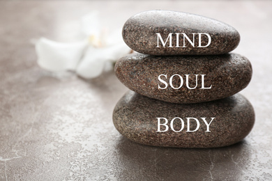 Photo of Stones with words MIND, BODY, SOUL on brown marble background, space for text. Zen lifestyle