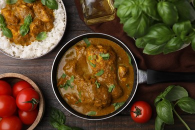 Delicious rice and chicken with curry sauce served on wooden table, flat lay