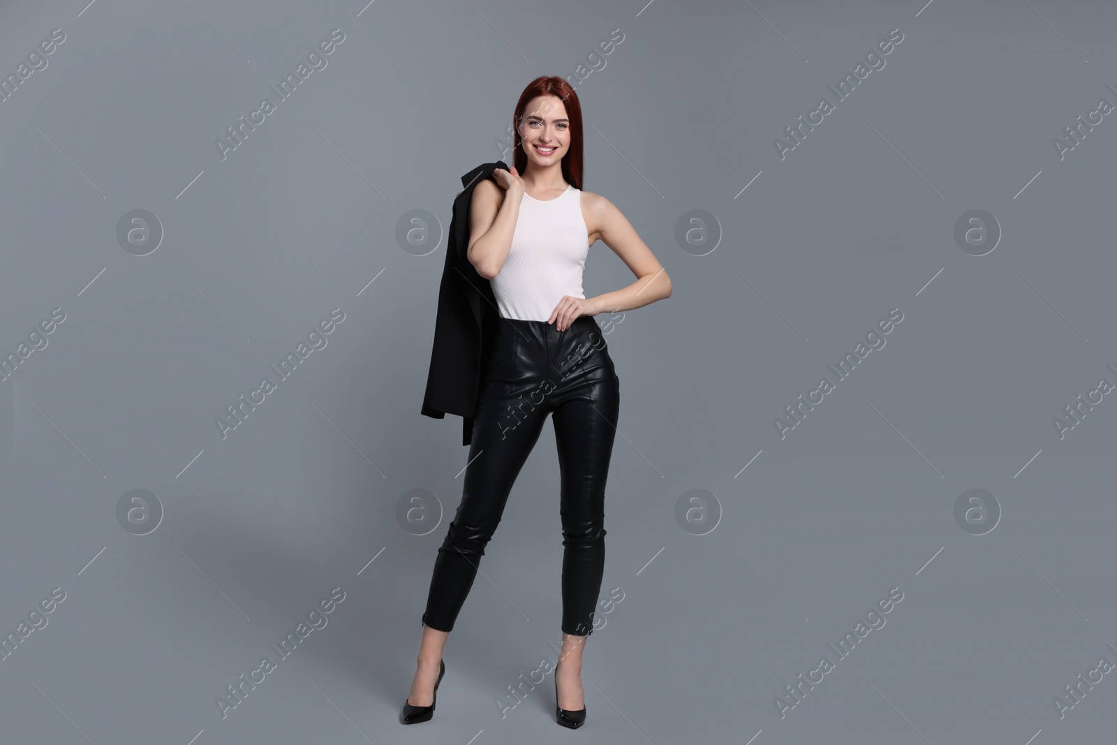 Photo of Stylish woman with red dyed hair posing on light gray background