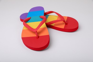 Photo of Stylish rainbow flip flops on white background