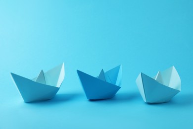 Photo of Handmade paper boats on light blue background. Origami art