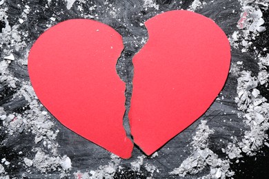 Photo of Halves of torn paper heart and ash on dark table, top view