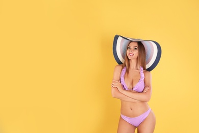 Photo of Pretty sexy woman in stylish bikini with hat on color background, space for text