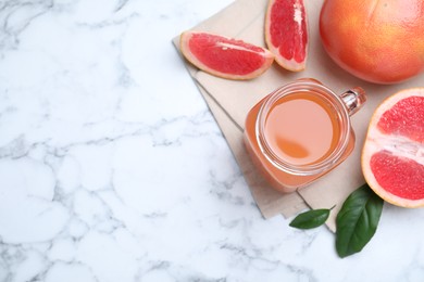 Photo of Tasty freshly made grapefruit juice and fruits on white marble table, flat lay. Space for text