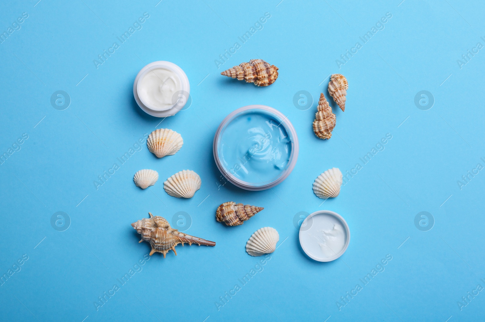 Photo of Flat lay composition with jars of body cream on light blue background