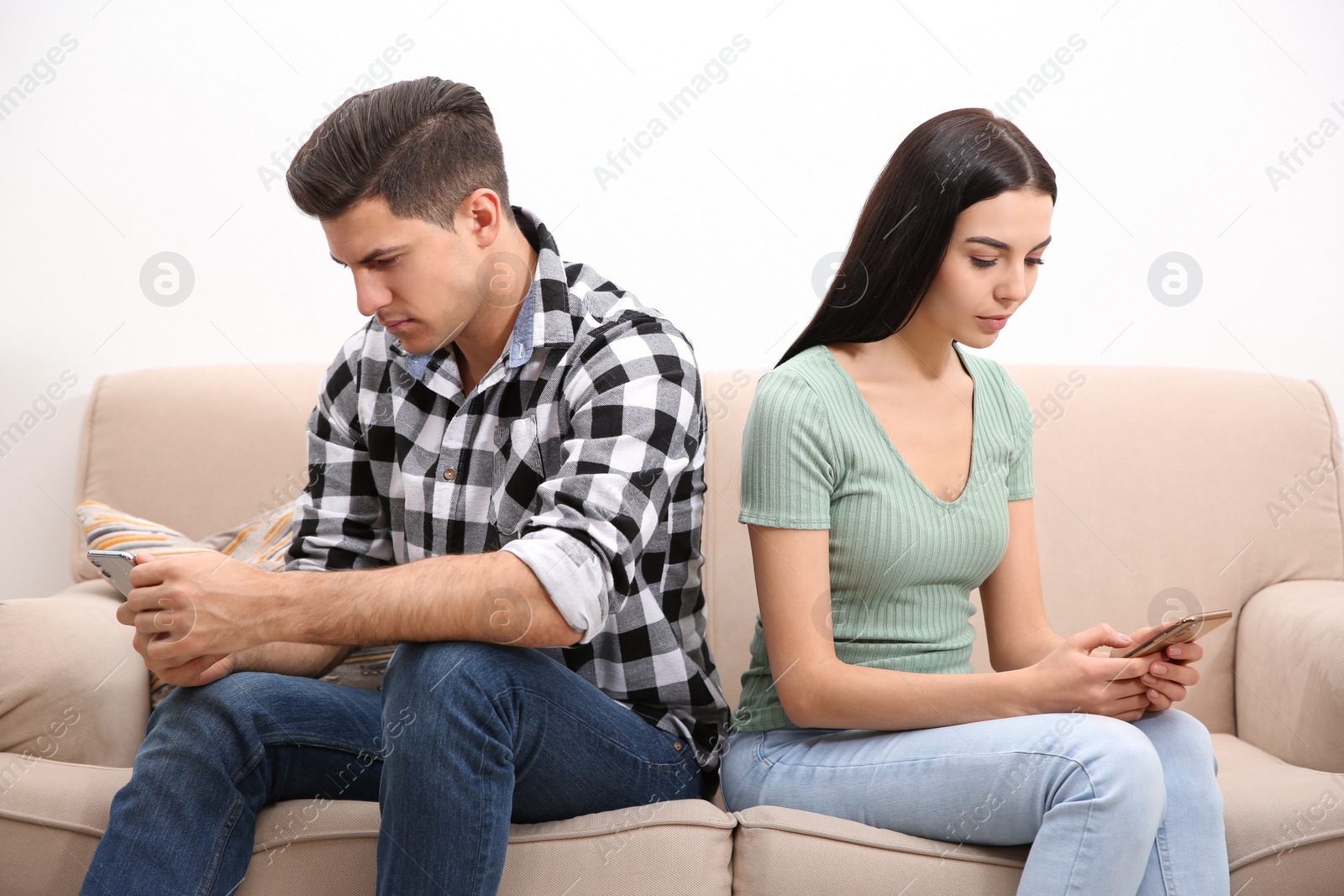 Photo of Couple addicted to smartphones ignoring each other at home. Relationship problems