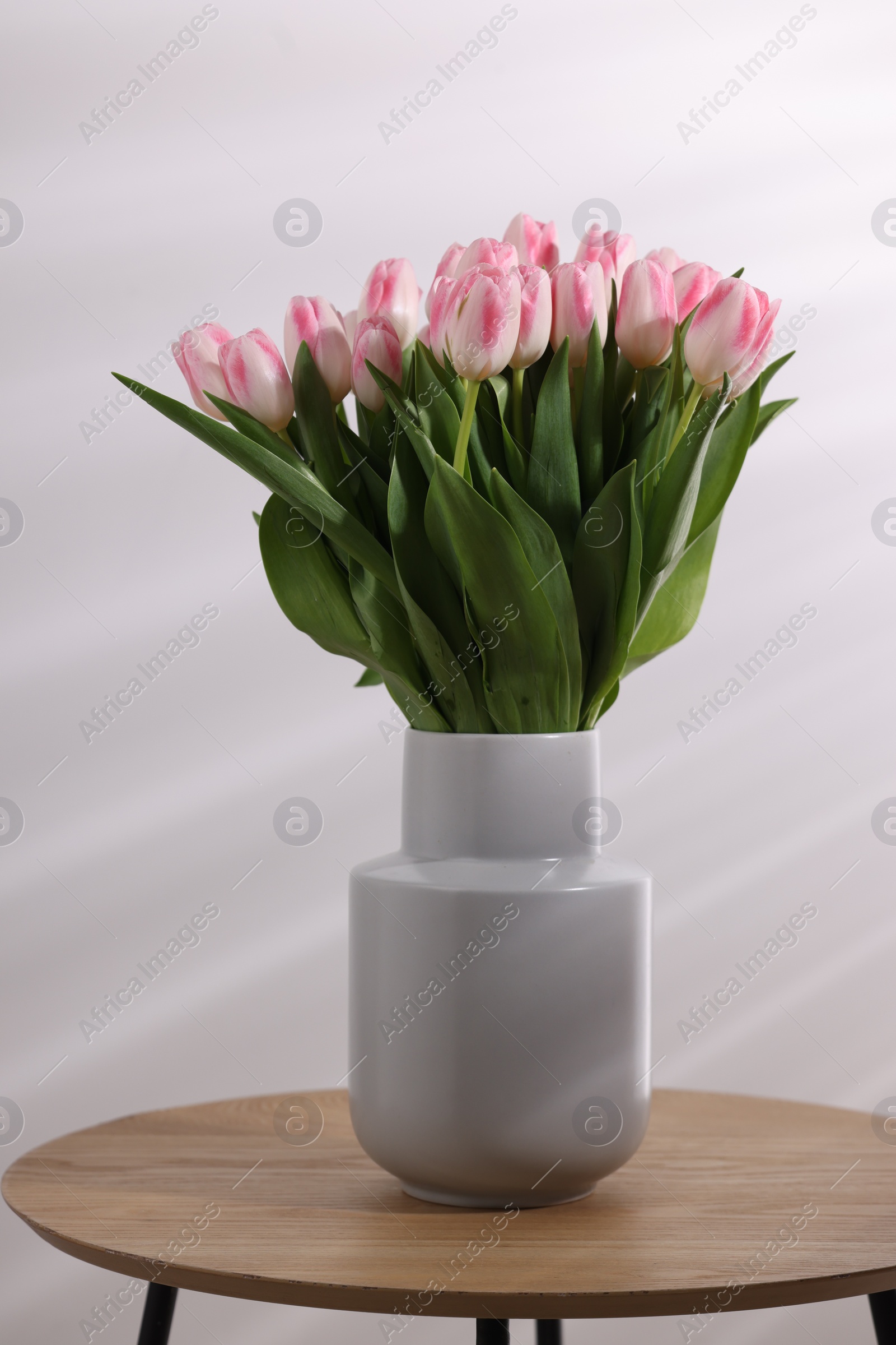 Photo of Beautiful bouquet of fresh pink tulips on table against light background