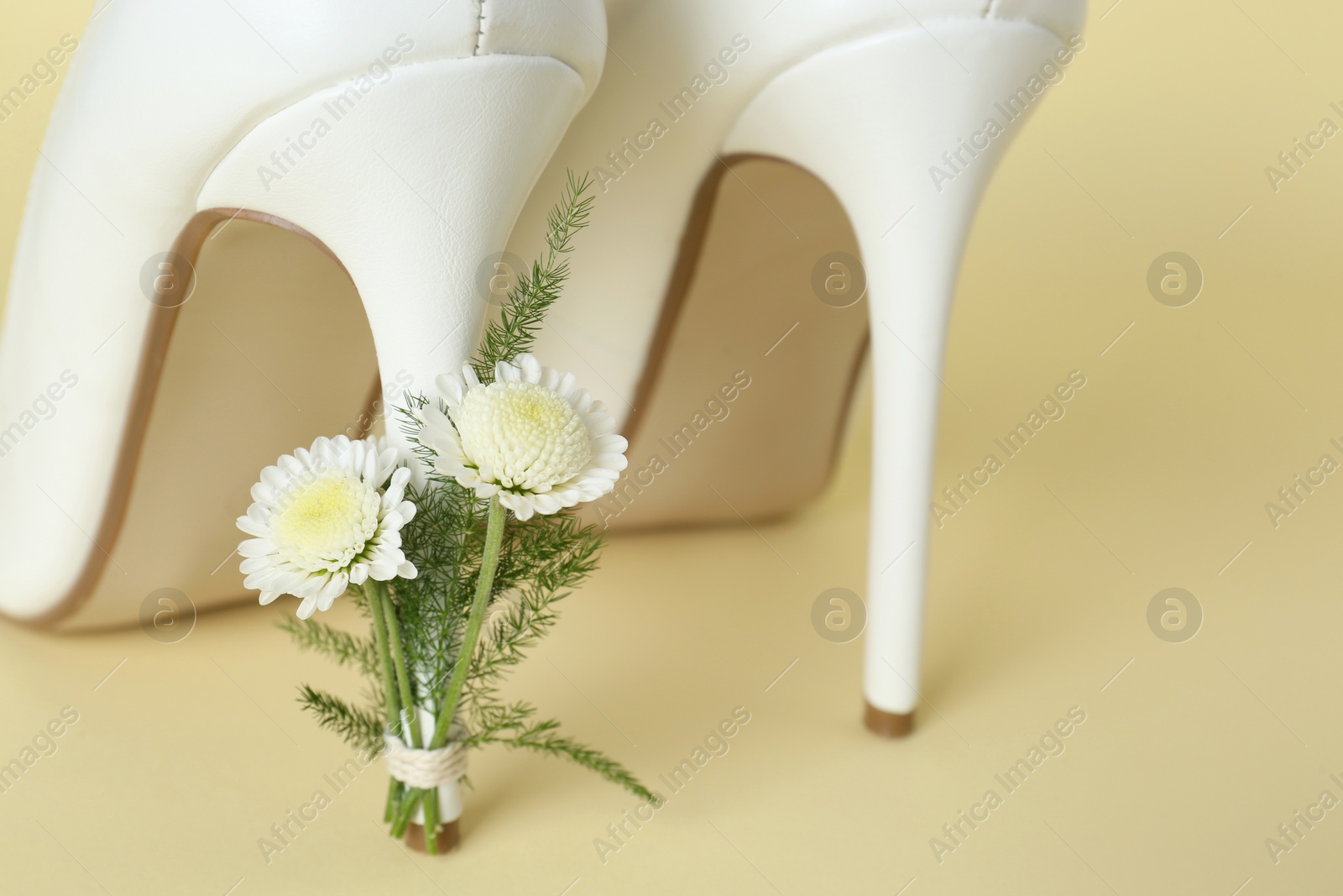 Photo of Stylish women's high heeled shoes with beautiful flowers on yellow background, closeup