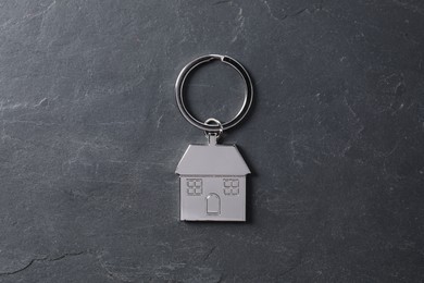 Metal keychain in shape of house on dark textured table, top view