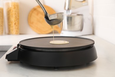 Photo of Cooking delicious crepe on electric pancake maker in kitchen, closeup