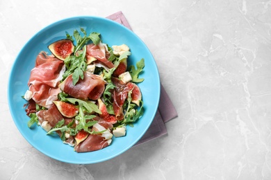 Photo of Salad with ripe figs and prosciutto served on grey marble table, top view. Space for text