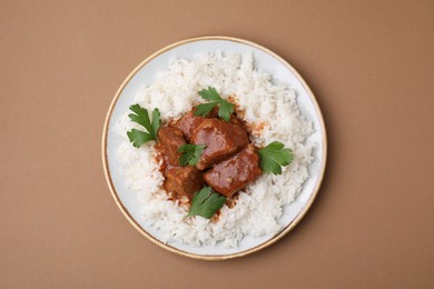 Photo of Delicious goulash with rice on brown background, top view