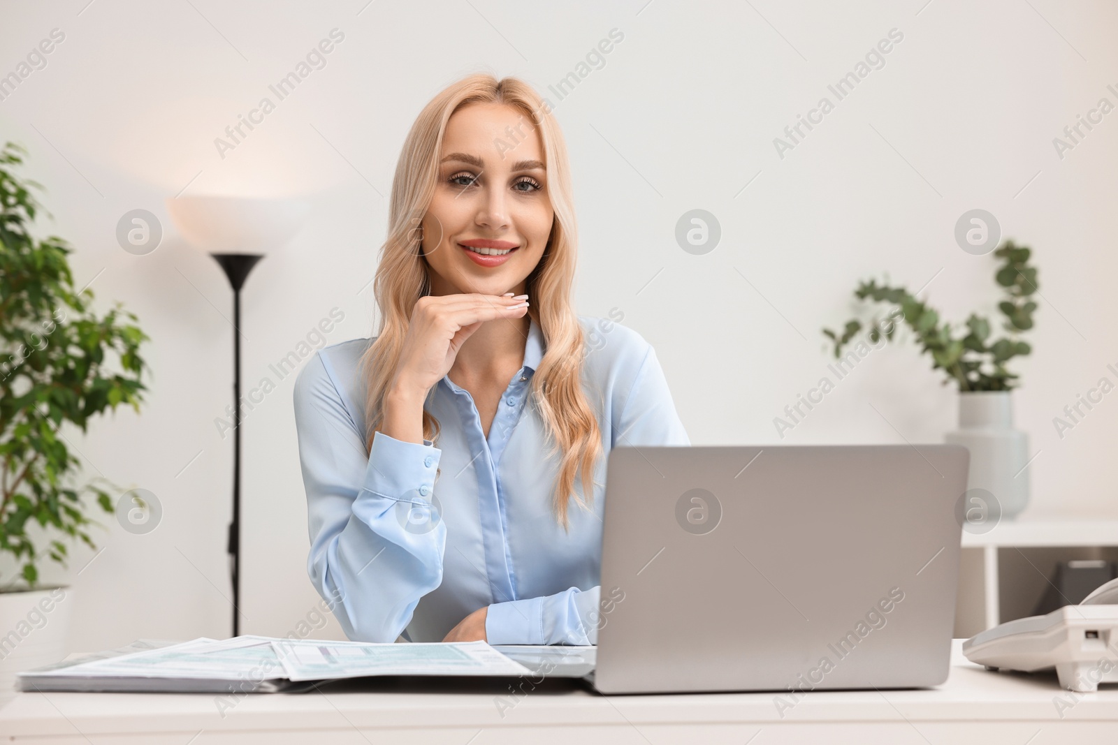 Photo of Happy secretary at table with laptop in office