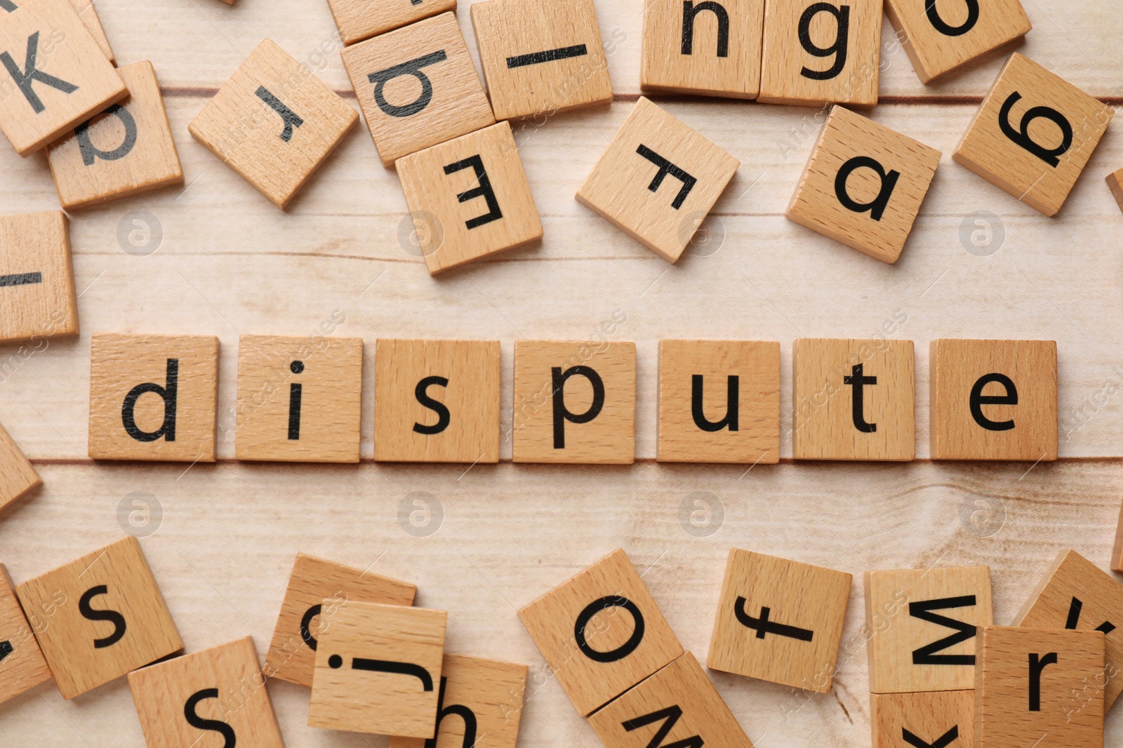 Photo of Squares with word Dispute on light wooden table, flat lay