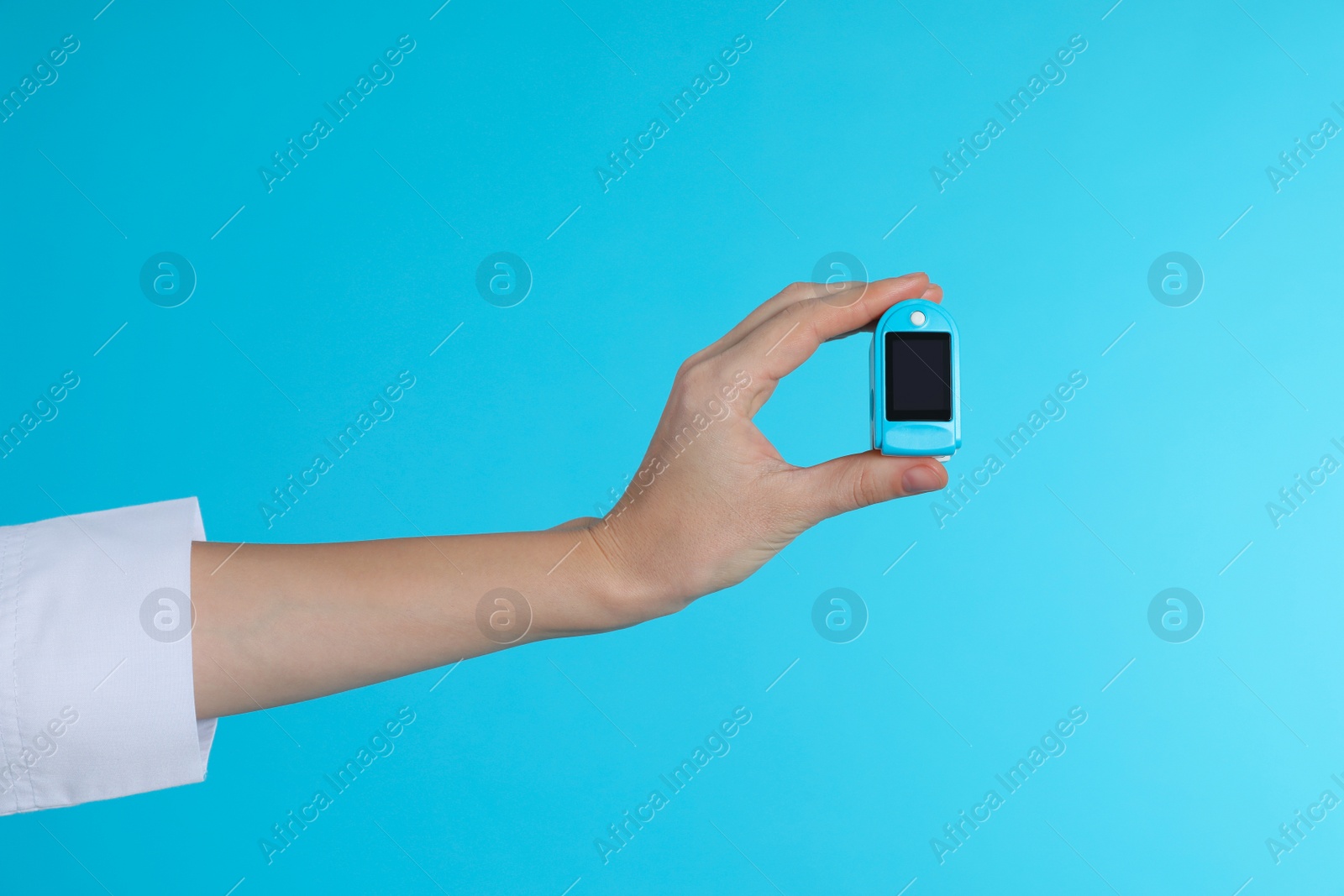 Photo of Female doctor holding pulsimeter on color background, closeup. Medical object