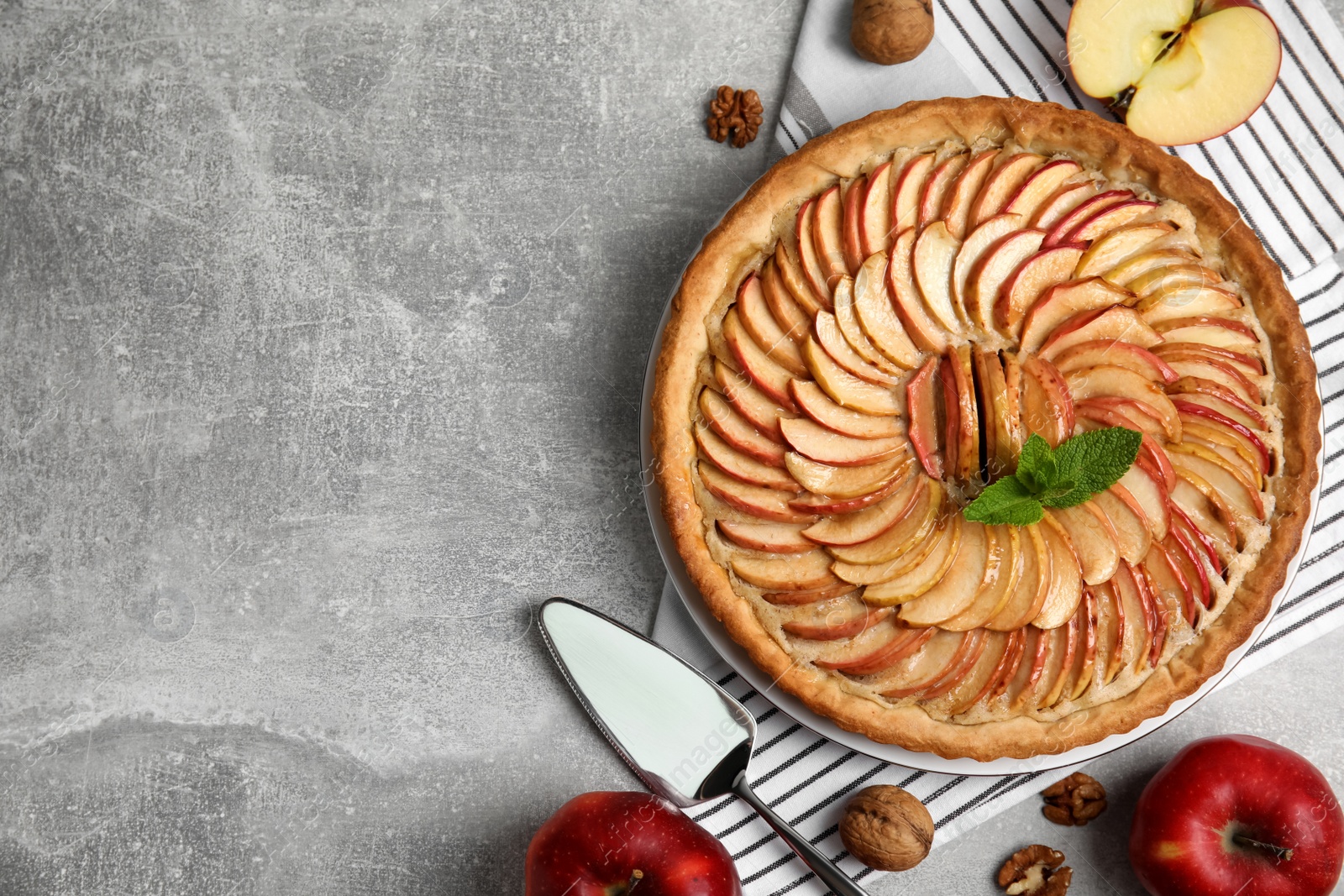 Photo of Flat lay composition with delicious homemade apple tart on grey table. Space for text