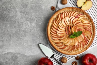 Flat lay composition with delicious homemade apple tart on grey table. Space for text