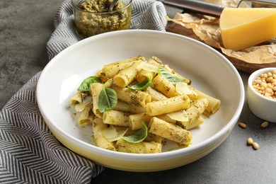 Plate with delicious basil pesto pasta on gray table