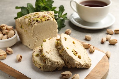 Photo of Tasty halva with pistachios served on grey table, closeup