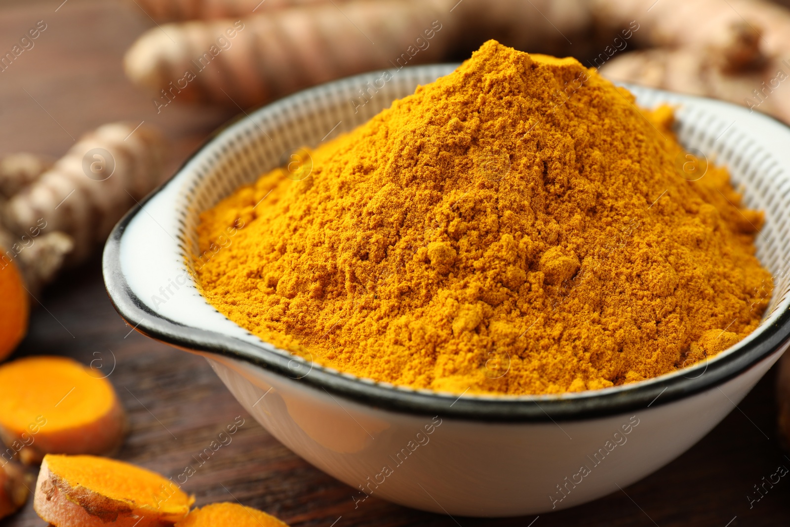 Photo of Bowl with aromatic turmeric powder on table, closeup