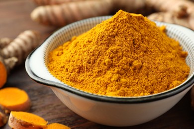 Bowl with aromatic turmeric powder on table, closeup