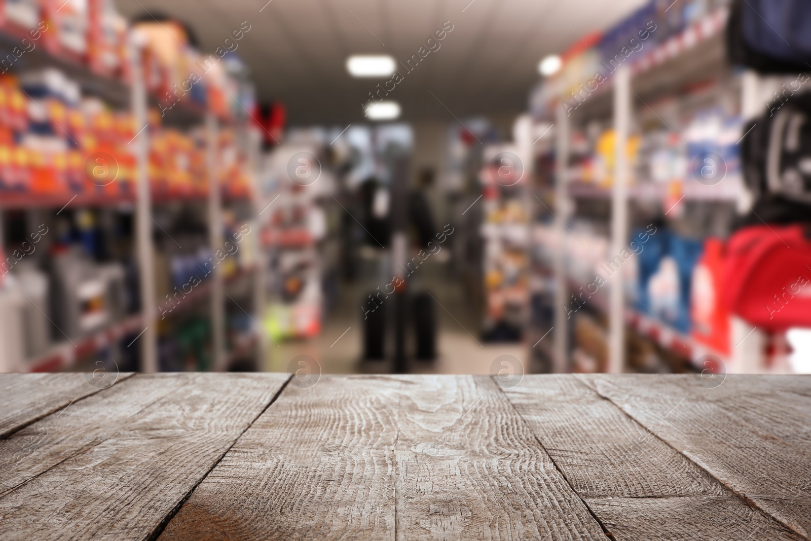 Image of Empty wooden surface and blurred view of car tires in auto store, closeup. Space for text 