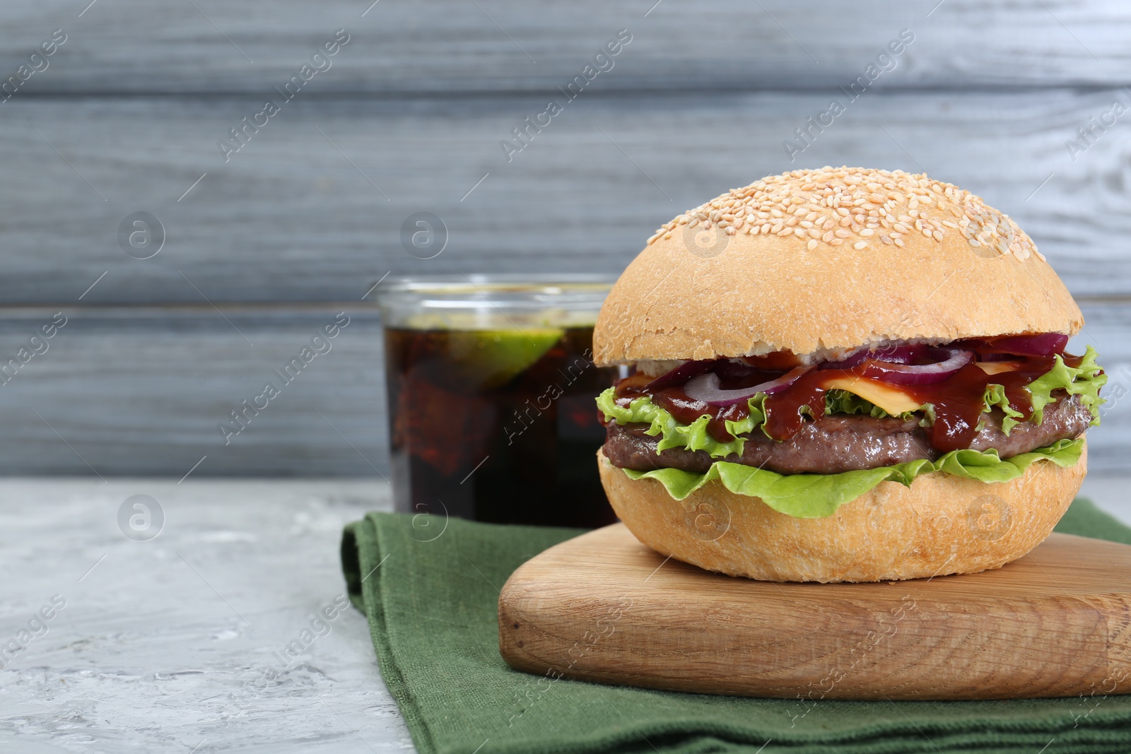 Photo of Delicious cheeseburger on grey textured table, closeup. Space for text