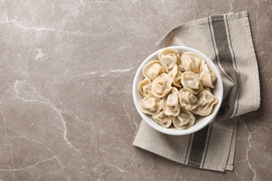 Photo of Tasty dumplings in bowl on marble table, flat lay. Space for text