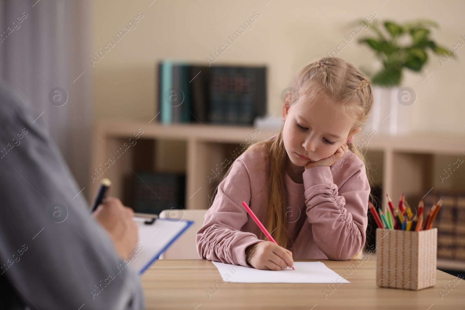 Photo of Little girl on appointment with child psychotherapist indoors