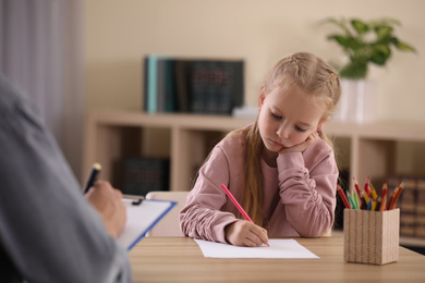 Little girl on appointment with child psychotherapist indoors