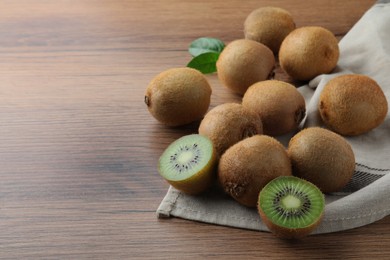 Photo of Fresh ripe kiwis on wooden table, space for text