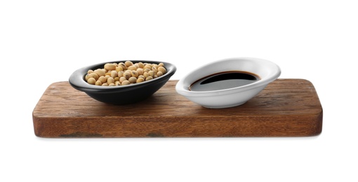 Photo of Wooden board with dishes of soy sauce and beans on white background