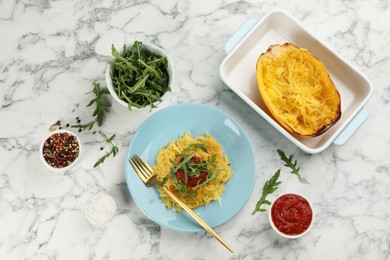 Photo of Tasty spaghetti squash with arugula and tomato served on white marble table, flat lay