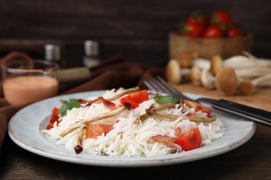 Photo of Delicious rice with bacon, mushrooms and tomatoes served on table, closeup